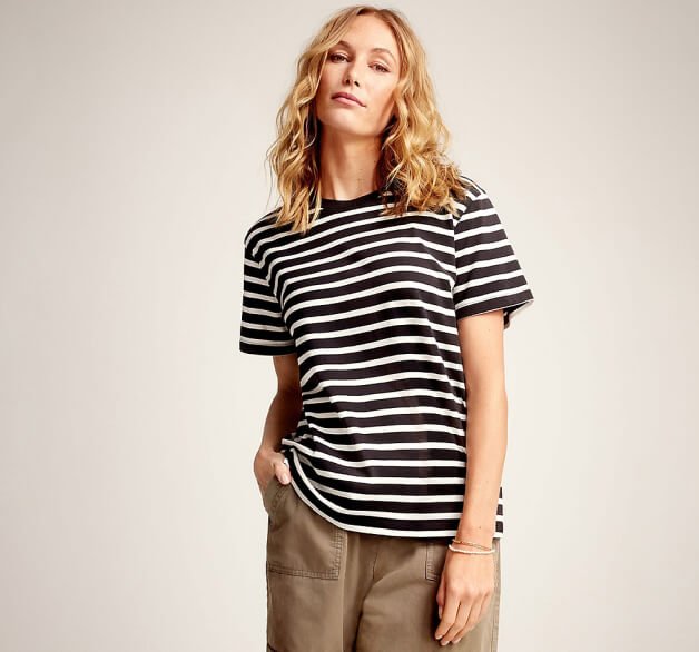 A woman posing in a black striped top and khaki trousers